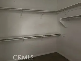 Spacious walk-in closet offering shelving and generous hanging space.