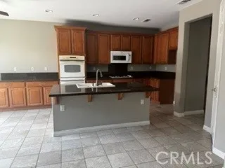 Spacious kitchen featuring abundant wood cabinetry, granite countertops, breakfast bar, and tile flooring.