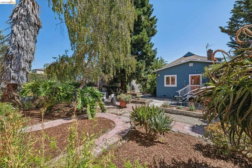 Expansive backyard with brick-edged pathways, mulched garden beds, mature trees, and established plantings