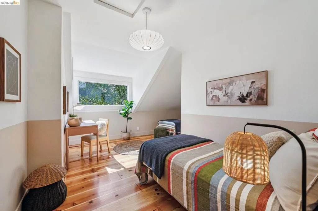 Hardwood flooring, sloped ceiling design, natural lighting, white walls, and built-in window