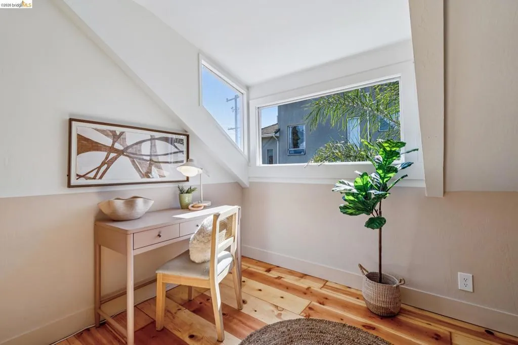 Angled ceiling design, wood-finish flooring, white window frames, and two-tone wall treatment
