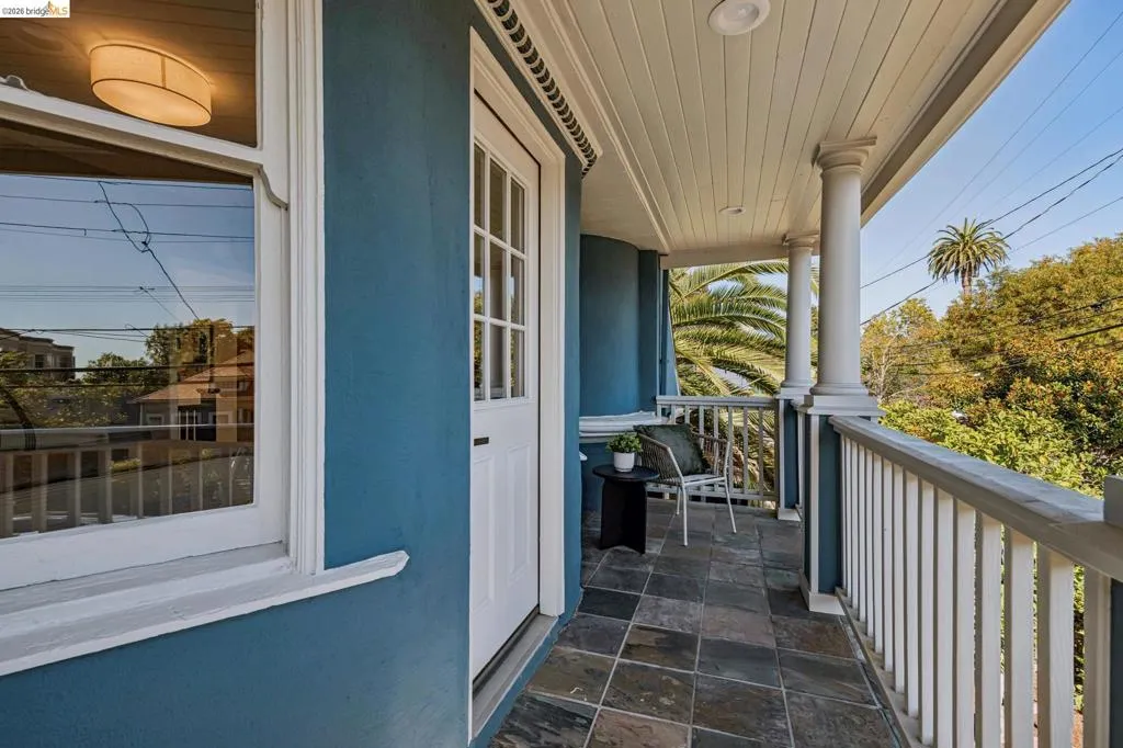 Covered balcony featuring a tiled floor, white balusters, and fluted columns
