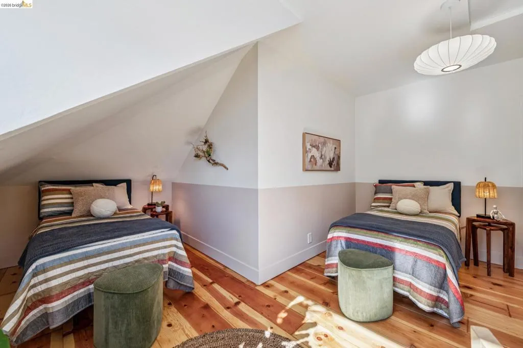 Wood-finish flooring, accent wall, sloped ceiling, and a distinct ceiling light fixture