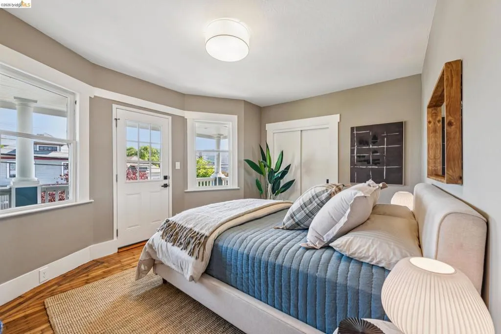 Wood-finish flooring, white trim details, ceiling-mounted light fixture, sliding closet doors, and multiple windows