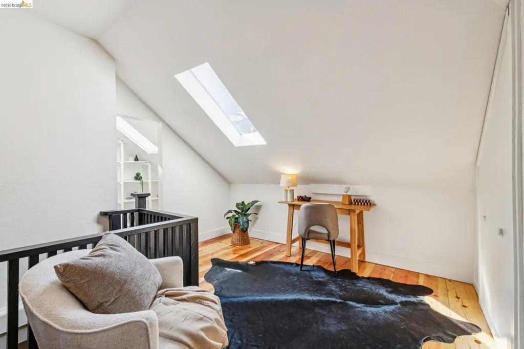 Hardwood flooring, sloped ceiling, skylight, built-in shelving, white walls