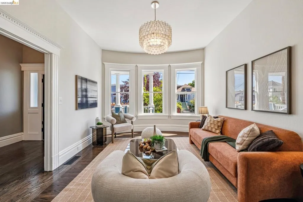 Hardwood flooring throughout, a decorative ceiling light fixture, crown molding, and large bay windows