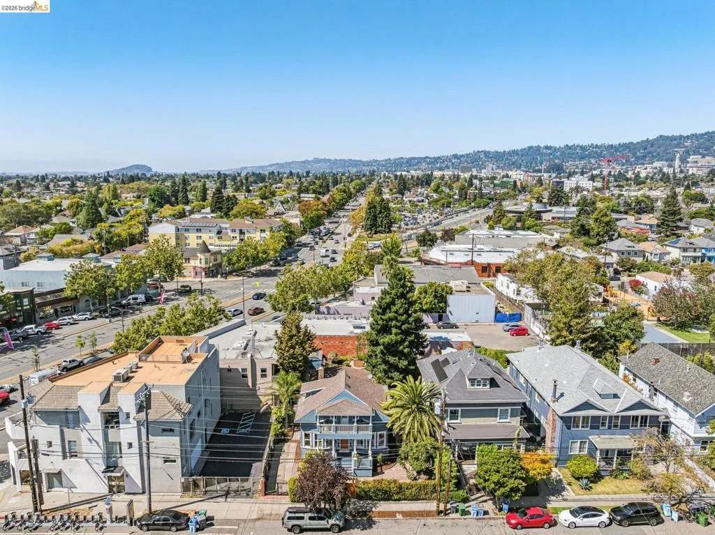 Residential properties with varied architectural styles, tree-lined streets, distant hills, and commercial establishments