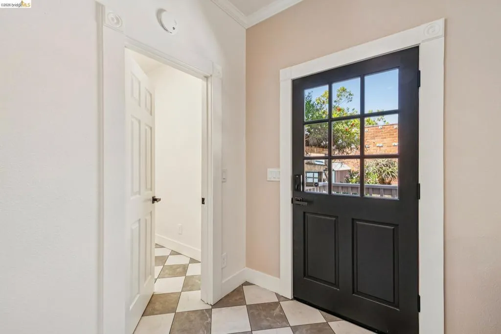Black paneled door with glass inserts, white trim with corner blocks, and a checkered tile floor