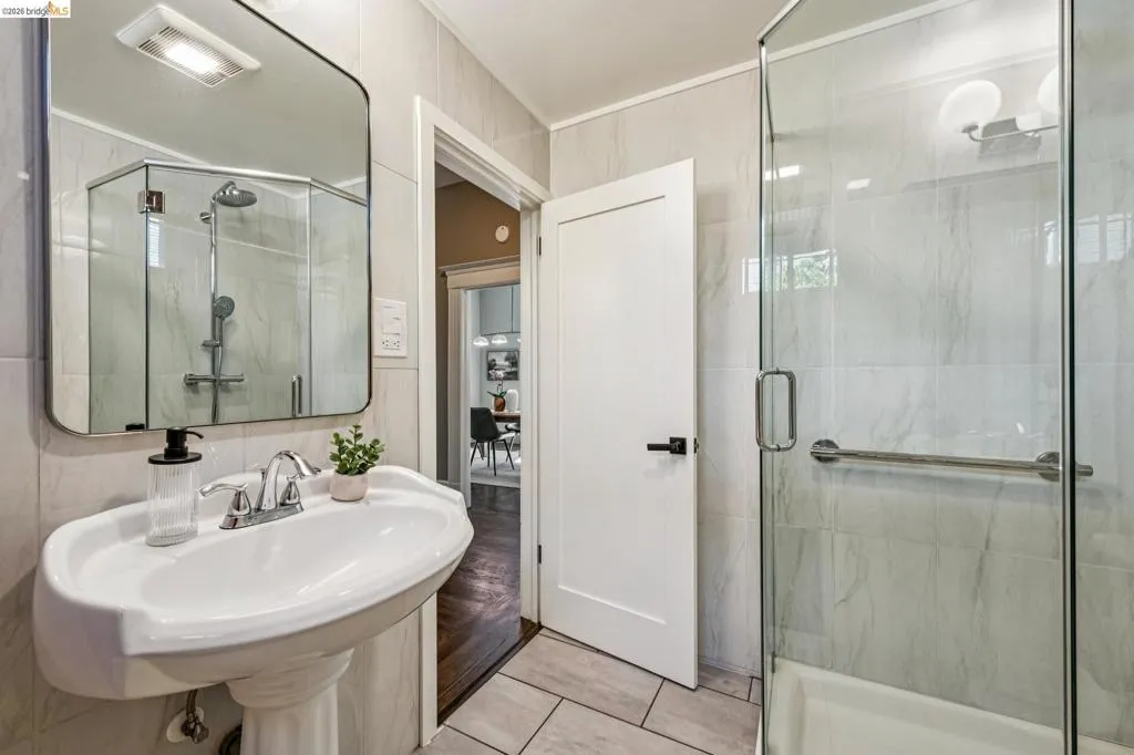 Pedestal sink with chrome faucet, walk-in shower with glass enclosure, light-toned wall tile, and recessed overhead lighting