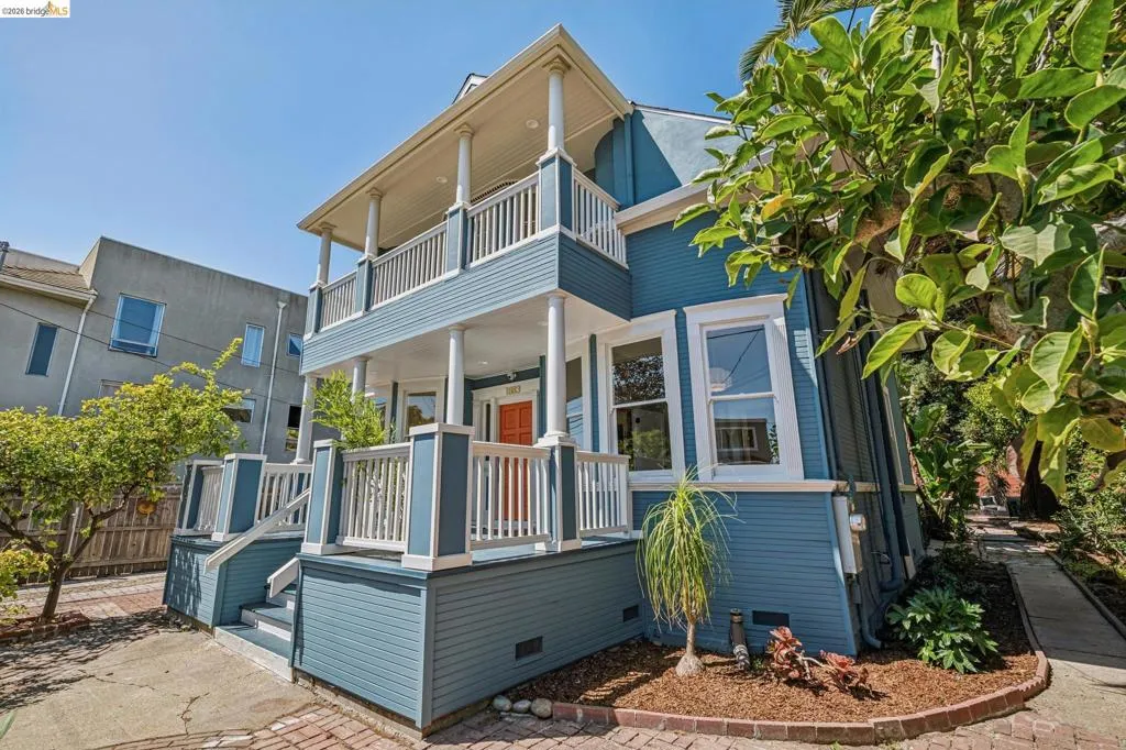 Two-story exterior with a double-stacked porch, upper and lower railings, and a brick-paved walkway