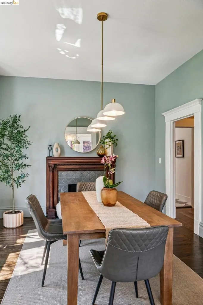Wood-finish flooring, decorative fireplace with tile surround, white trim, and a linear pendant light fixture