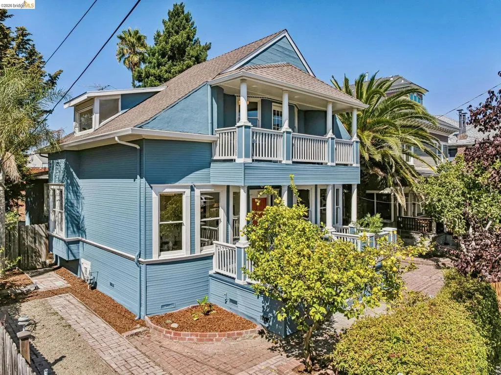 Two-story residence with a covered balcony, front porch, dormer window, and brick-laid pathways