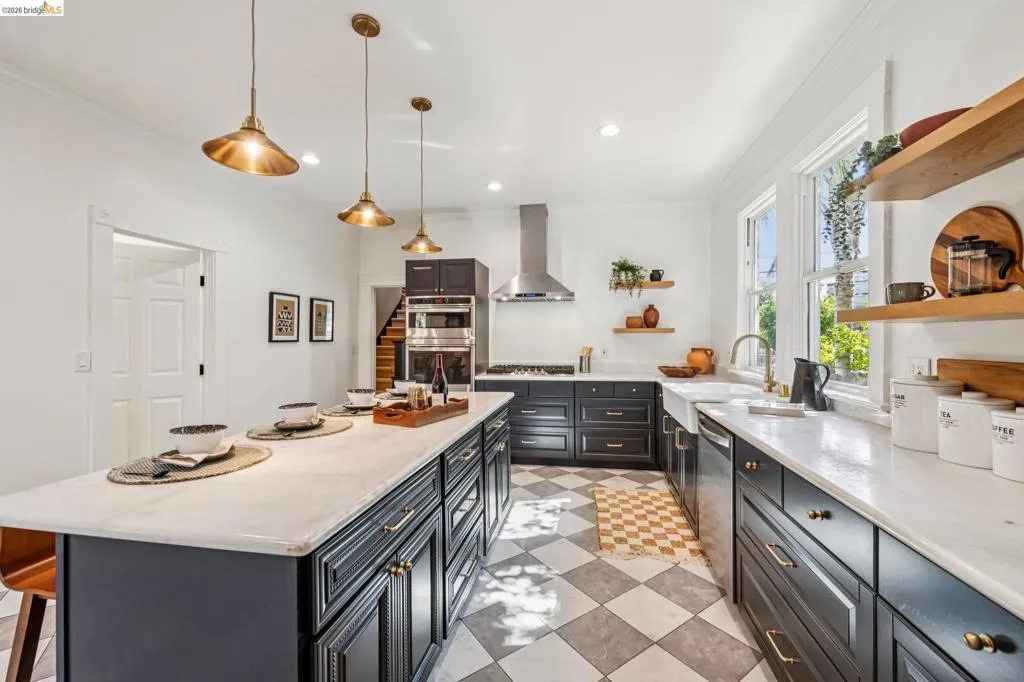 Spacious kitchen featuring a large central island, dark cabinetry, light countertops, and checkered flooring