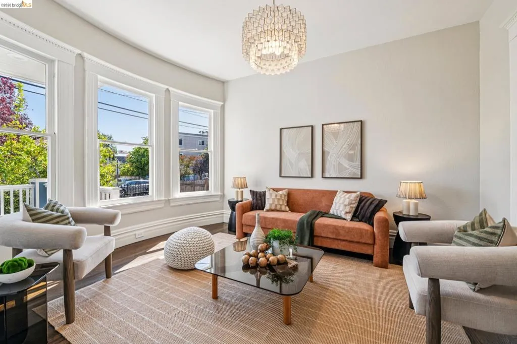 Hardwood flooring, curved bay window, decorative crown molding, and a contemporary chandelier
