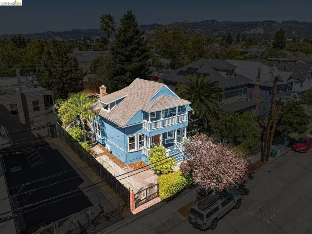 Two-story residence with a light blue exterior, featuring a private driveway, gated entry, and established landscaping