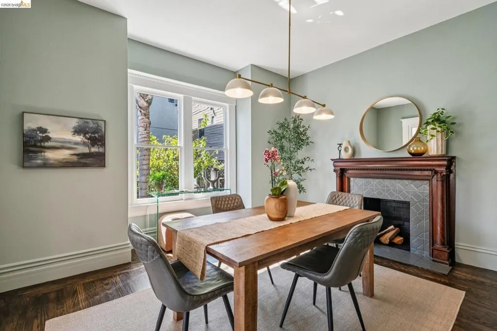 Hardwood flooring, decorative fireplace with tiled surround, crown molding, modern linear chandelier, and a large window