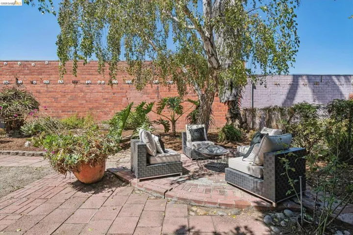 Brick paver patio with a central gathering area, mature tree, and surrounding landscaping
