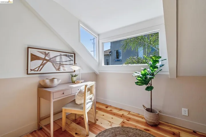 Angled ceiling design, wood-finish flooring, white window frames, and two-tone wall treatment