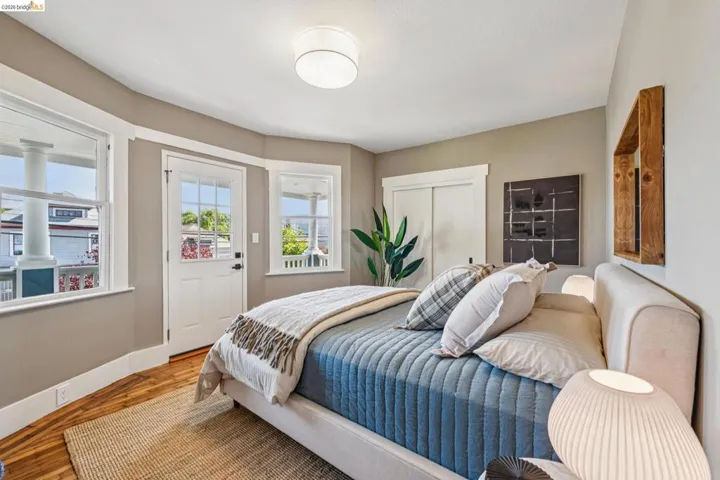 Wood-finish flooring, white trim details, ceiling-mounted light fixture, sliding closet doors, and multiple windows