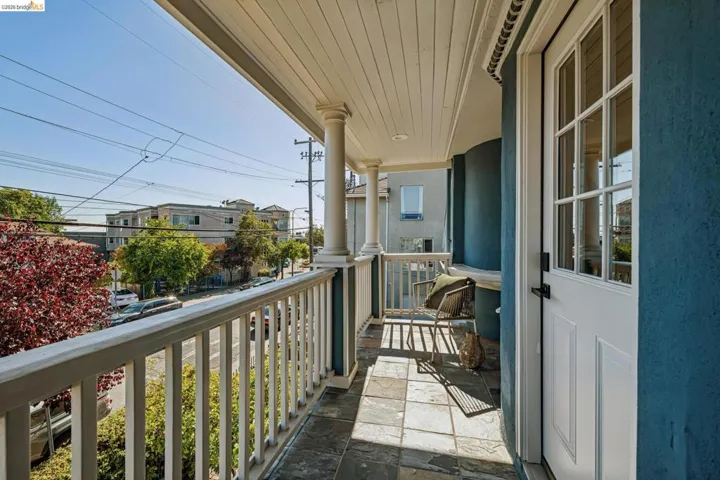 Balcony with slate tile flooring, white balustrade, and beadboard ceiling
