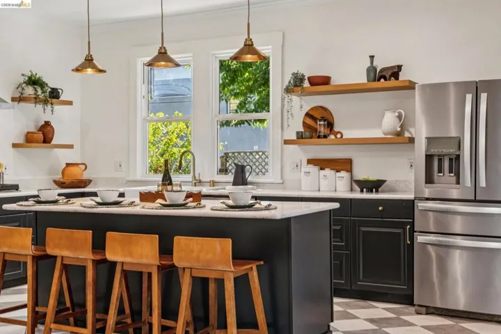 Kitchen featuring a central island, dark cabinetry, stainless steel appliances, floating wood shelving, and checkered flooring