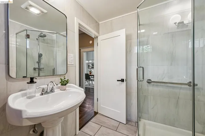 Pedestal sink with chrome faucet, walk-in shower with glass enclosure, light-toned wall tile, and recessed overhead lighting