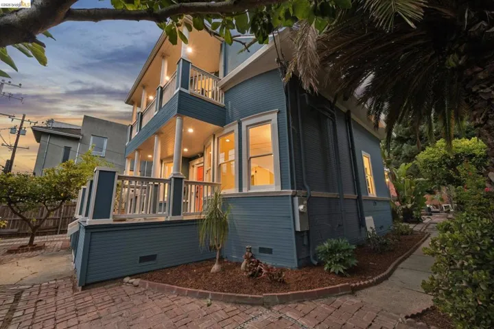 Two-story exterior with a covered upper balcony and lower porch, substantial columns, and a brick paver driveway