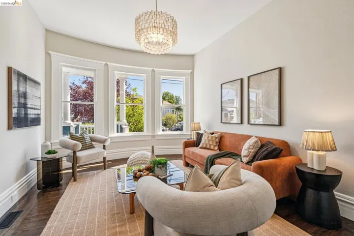 Bay window with multiple double-hung windows, high ceilings, wood-finish flooring, and a decorative chandelier