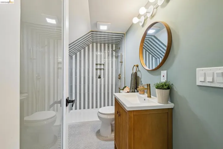 Walk-in shower with vertical striped tile, glass enclosure, and built-in niche