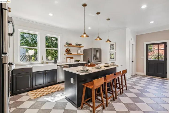 Kitchen featuring a large island with seating, pendant lighting, stainless steel appliances, and a farmhouse sink