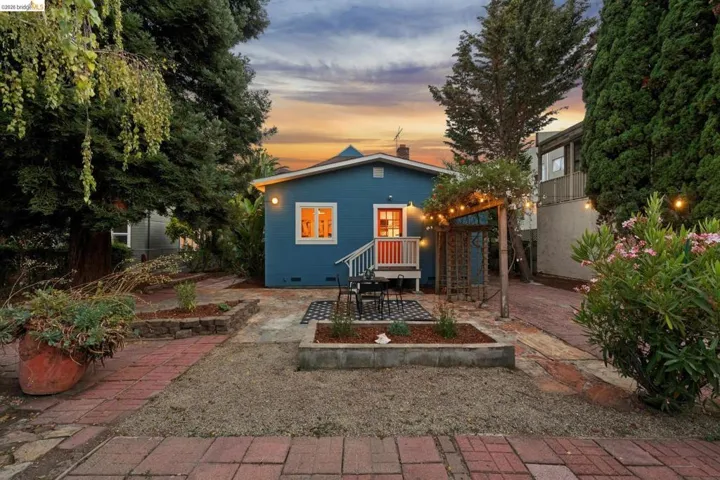 Blue exterior siding with white trim, red front door, white porch railing, and a pergola structure