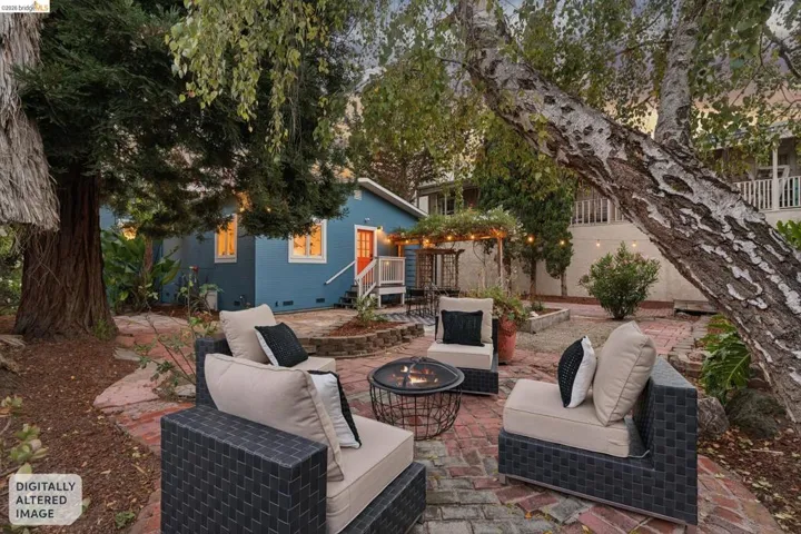 Rear exterior featuring a vibrant blue siding, red entry door, white trim, and an expansive brick-paved patio