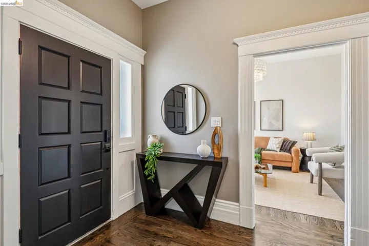 Paneled entry door with sidelight, wood-finish flooring, and crown molding detailing