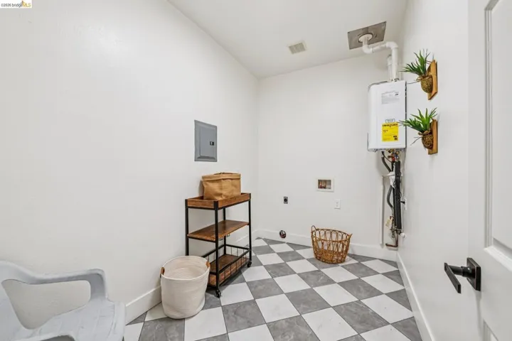 Black and white checkered flooring with a contemporary wall-mounted water heater and an electrical panel