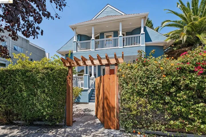 Blue exterior with white trim, wood gate, and trellis entry