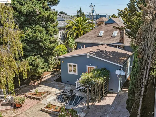 Multi-level backyard space with diverse landscaping, featuring a paved patio area and mature perimeter trees