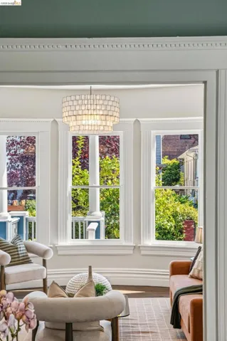 Decorative crown molding, white trim, multi-pane windows, and a tiered chandelier