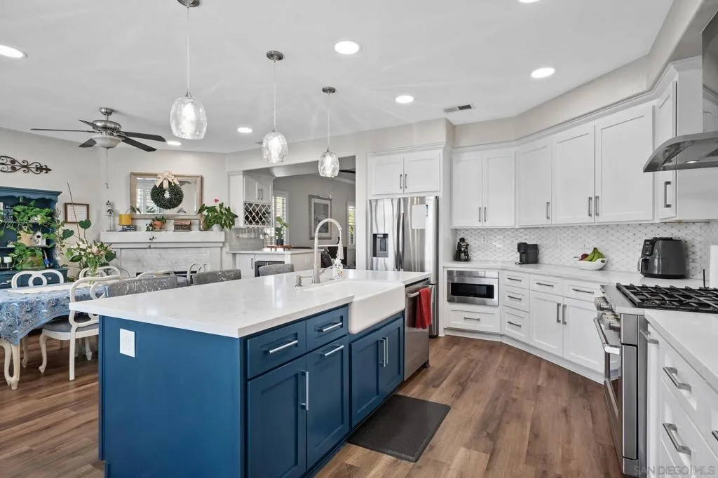 Remodeled kitchen featuring quartz countertops, custom cabinetry with pull-out shelving and soft-close drawers, a Kohler farmhouse sink, microwave drawer, and 36" GE Café professional-style stainless-steel gas range.