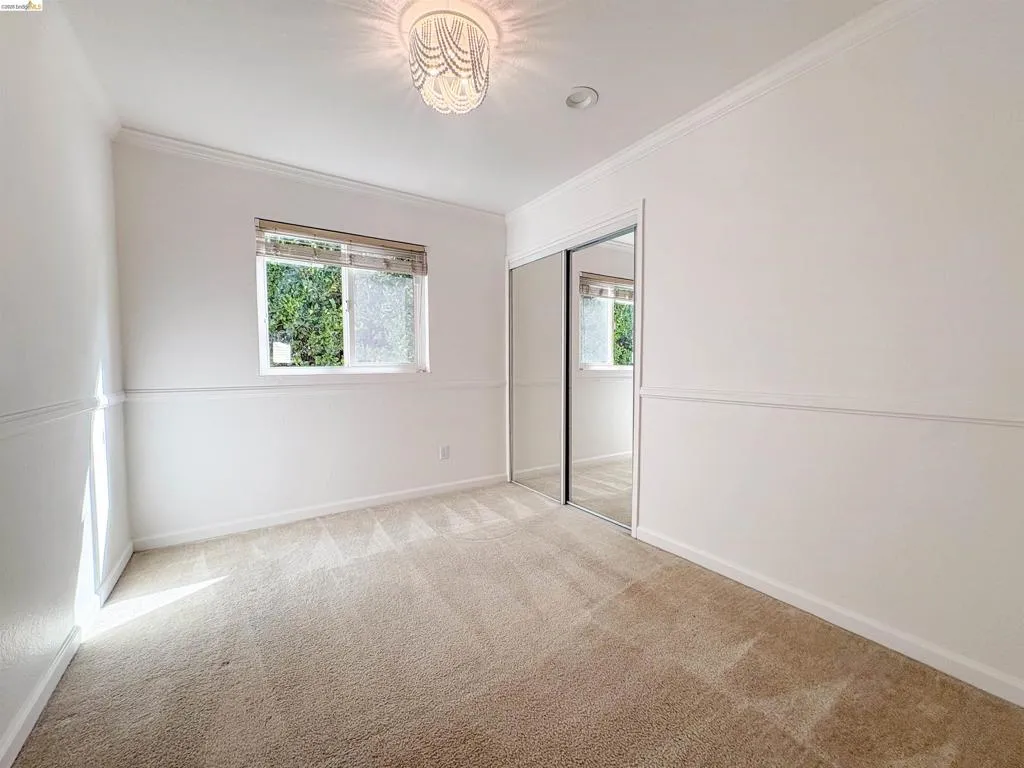 Neutral-toned wall-to-wall carpeting, crown molding, and a contemporary ceiling fixture
