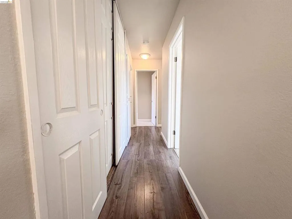 Hallway featuring wood-finish flooring, light-colored walls, recessed ceiling lighting, and paneled doors