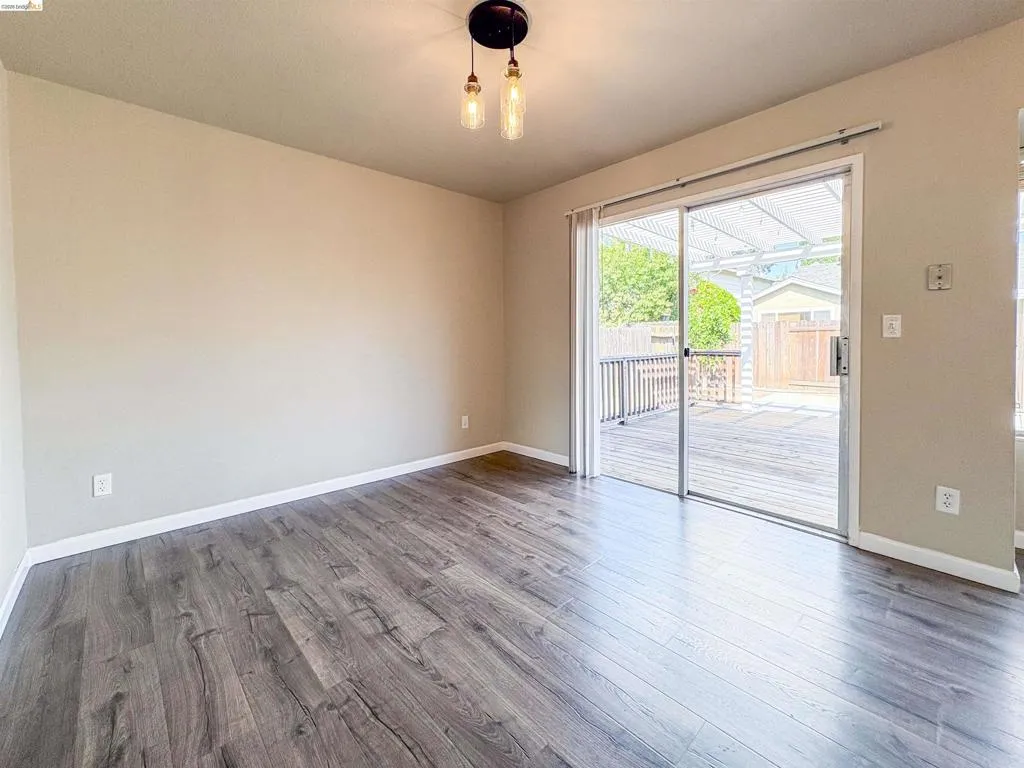 Wood-finish flooring, sliding glass door, overhead lighting fixture, and a spacious outdoor deck
