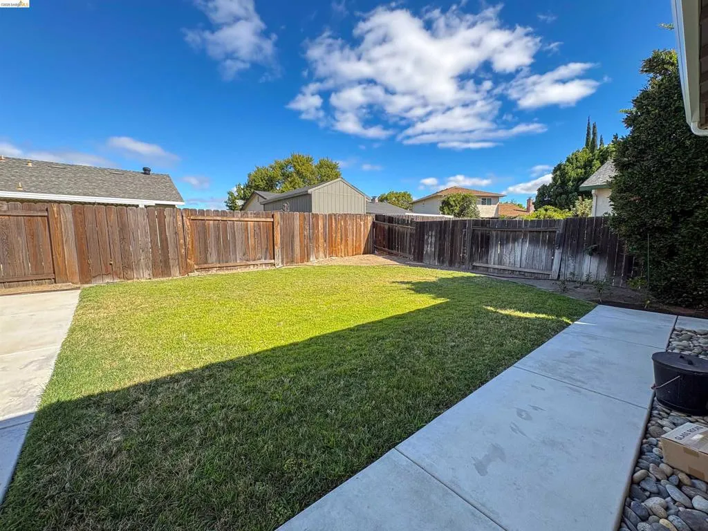 Expansive backyard featuring a manicured lawn, perimeter fencing, and concrete patio