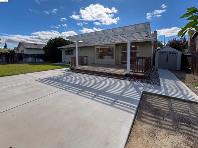 Expansive concrete patio with a wooden deck and white pergola