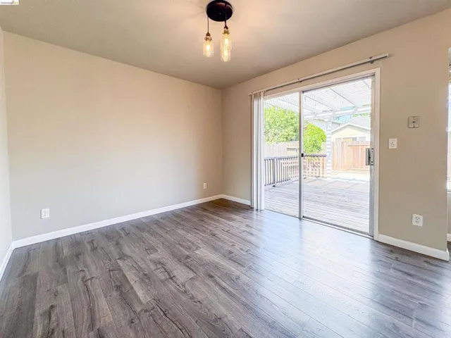 Wood-finish flooring, sliding glass door, overhead lighting fixture, and a spacious outdoor deck