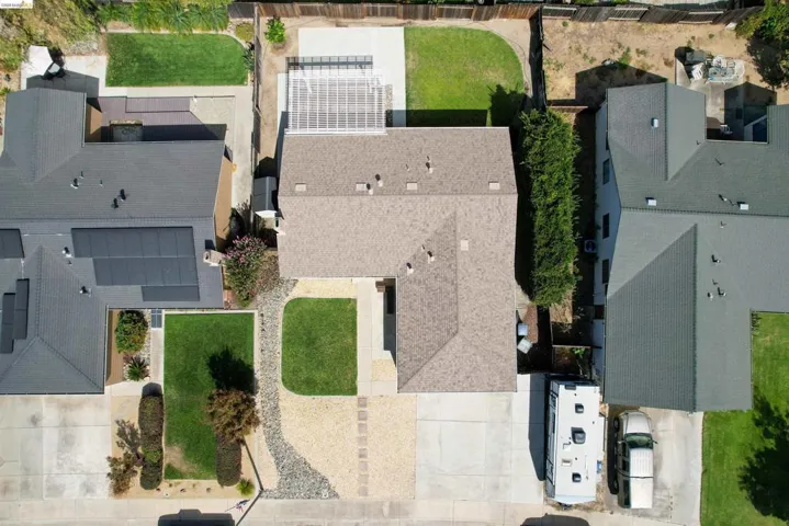 Expansive driveway with gravel and concrete sections, complemented by a front lawn and landscaping