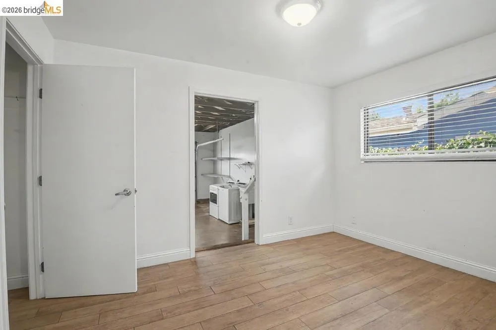 Wood-finish flooring, white walls, and a window with blinds