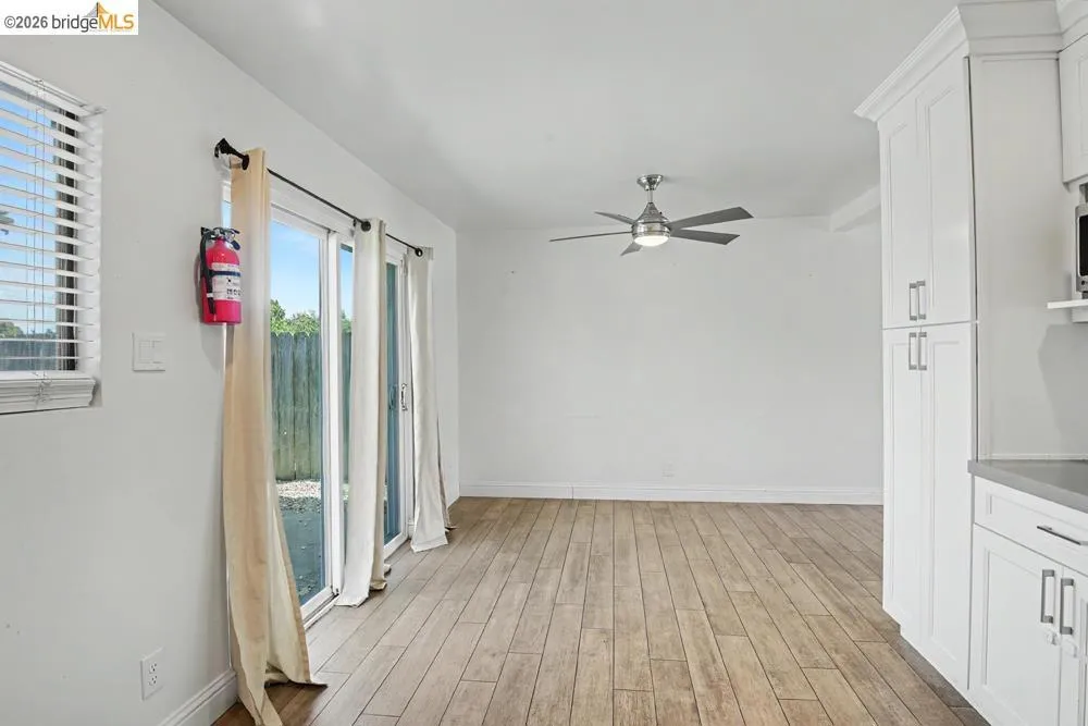 Wood-finish flooring, white cabinetry, a contemporary ceiling fan, and a sliding glass door providing exterior access