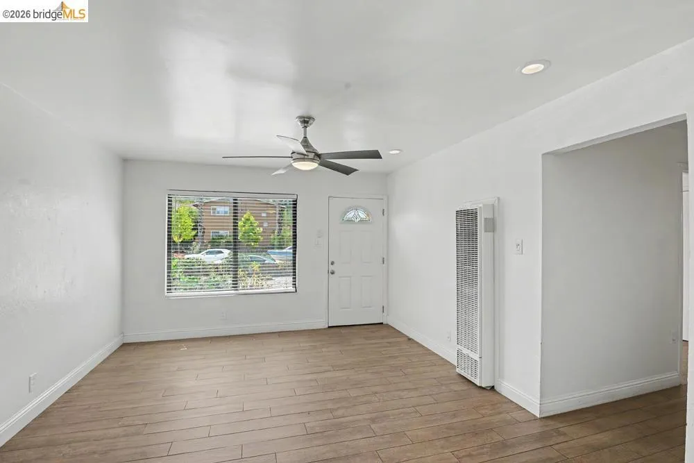Wood-finish flooring, recessed lighting, ceiling fan, and white walls