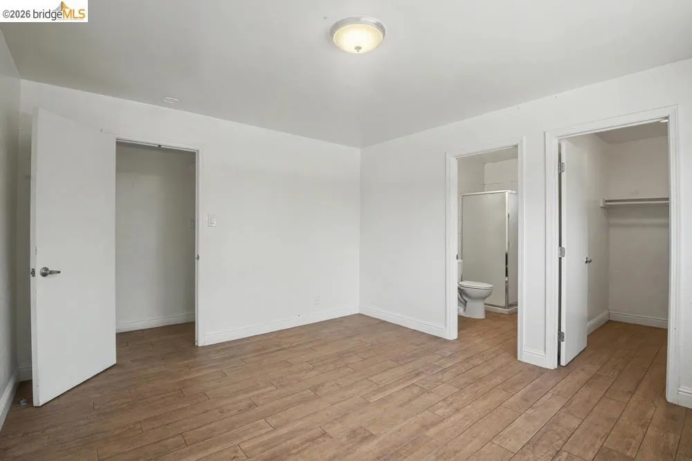 Wood-finish flooring, white walls, flush mount ceiling light, and white interior doors