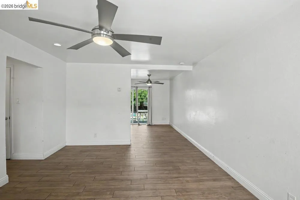 Wood-finish flooring throughout, bright white walls, modern ceiling fans with integrated lighting, recessed lighting, and patio access